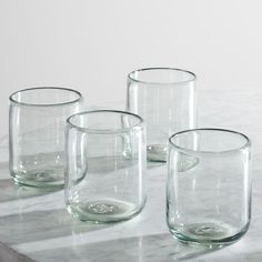 three clear glass cups sitting on top of a marble table