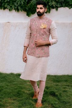 Featuring a peach bundi jacket in raw silk base with floral thread work. It is paired with matching churidar pants and an ivory kurta.  FIT: True to size. COMPOSITION: Raw silk. CARE: Dry clean only. Engagement Dress For Groom, Indian Wedding Suits Men, Wedding Outfits For Groom