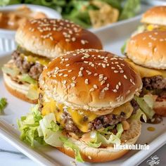 three cheeseburgers with lettuce and tomato on a plate