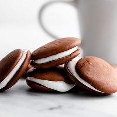 three cookies with white frosting on them next to a cup