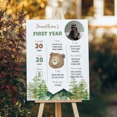 a sign with a bear on it in front of some bushes and trees that says, first year