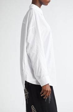 A perfect staid complement to the Belgian designer's avant-garde glamour, the classic cotton button-up shirt is recast in this comfortably relaxed rendition with dropped shoulders. 30 1/2" length (size Small) Front button closure Point collar Long sleeves with button cuffs Dropped shoulders Curved hem 100% cotton Dry clean or machine wash, line dry Imported Designer Clothing Oversized Cotton Blouse For Formal Occasions, Designer Cotton Button-up Blouse, Designer Cotton Blouse With Button Cuffs, Designer Relaxed Fit Button-up Shirt, Curved Hem Shirt, Drop Shoulder Shirt, Cotton Poplin Shirt, Dries Van Noten, Poplin Shirt