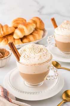 two cups filled with hot chocolate and topped with cinnamon sticks