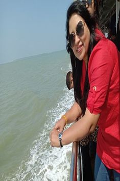 a woman standing next to a man on top of a boat in the ocean with people watching