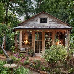 a small wooden house surrounded by trees and plants