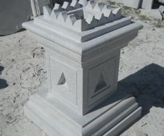 a cement monument sitting on top of a sandy ground next to other concrete structures in the background