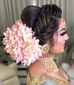 a woman with flowers in her hair and jewelry on top of her head, looking off to the side