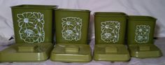 four green vases with white designs on them