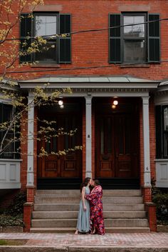 two people standing in front of a red brick building