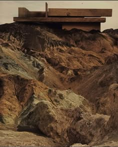 a wooden bench sitting on top of a rocky hill covered in dirt and rock formations