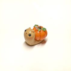 there is a small figurine of a bear with a pumpkin on its back