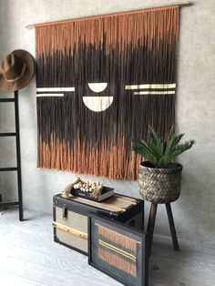 a room with a table, hat rack and wall hangings on the wall next to a potted plant