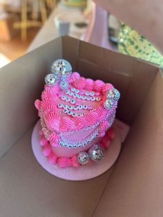 a pink cake in a box with lots of decorations on it's side and inside