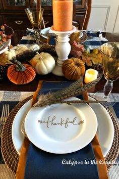 a thanksgiving table setting with candles and pumpkins