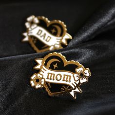 two pin badges with the words dad and heart on them, sitting next to each other