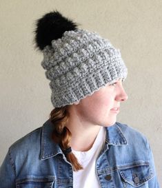 a woman wearing a gray hat with a black pom - pom