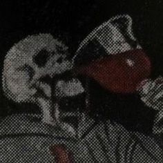 a man drinking from a beer glass in front of a black and white photo with skulls on it