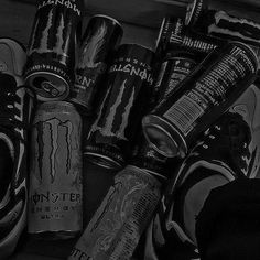 black and white photograph of monster energy drink cans with shoes on the floor next to them