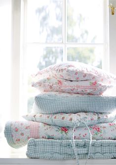 a stack of pillows sitting on top of a window sill