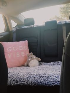 a stuffed animal laying on top of a pillow in the back seat of a car