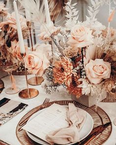 a table setting with flowers, candles and napkins on top of the place settings