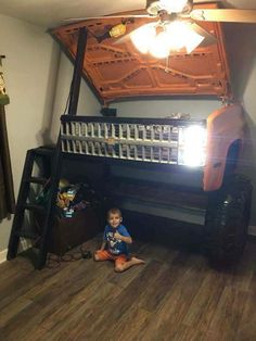 a small child sitting on the floor in front of a bunk bed with a ladder