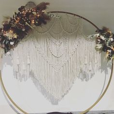 a white wall hanging decorated with flowers and feathers