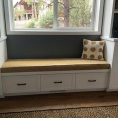 a window seat with a cushion on it next to a book shelf and bookshelf