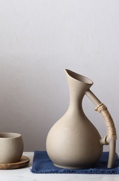 a white vase sitting on top of a table next to two cups