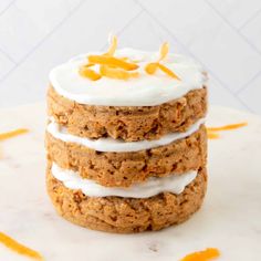 a stack of carrot cake sitting on top of a white cake plate with frosting