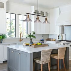 a large kitchen with white cabinets and gray island