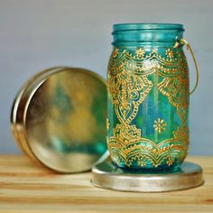 a green mason jar sitting on top of a wooden table next to a metal container