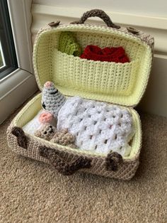 a crocheted suitcase is sitting on the floor next to a window sill