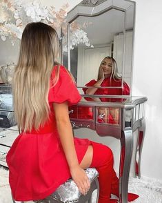 a woman sitting in front of a mirror looking at herself in the mirror and brushing her teeth