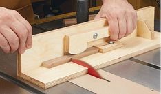 a person working on a piece of wood with a planer and a red tool