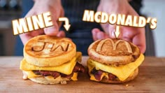 two breakfast sandwiches with the words mcdonald's written on them, and someone holding one