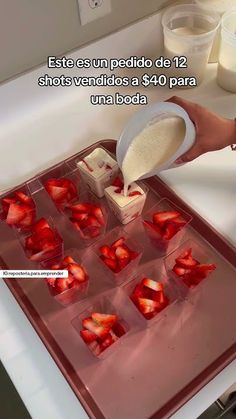 someone is pouring milk over strawberries on a tray