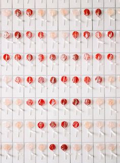 red and white lollipops are arranged in rows on a wall with pins attached to them