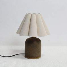 a table lamp with a white shade on it's base and a black cord