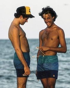 two men standing next to each other near the ocean