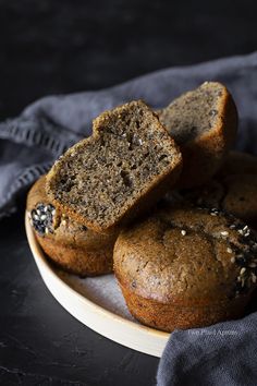 some muffins are on a plate and one is cut in half with sesame seeds