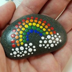 a hand holding a rock with different colored dots on it