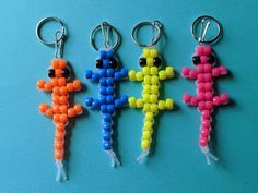 four key chains with different colored beads hanging from each one on a blue surface,