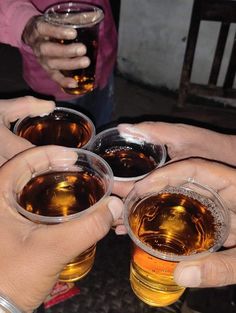 three people are holding their glasses with beer in them