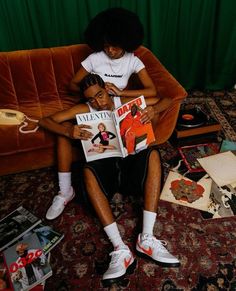 a woman sitting on top of a couch next to a man holding a magazine in his lap