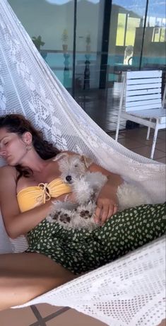 a woman laying in a hammock with her dog