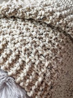 the blanket is crocheted with white yarn and has a fur ball on it