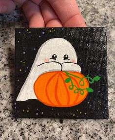 a painting of a ghost with a pumpkin on it's face is being held by someone