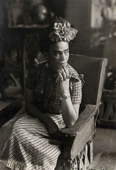 an old black and white photo of a woman sitting in a chair with her hand on her chin