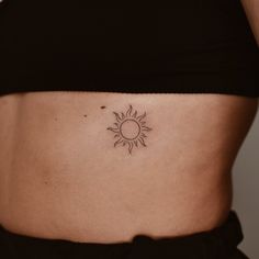 a woman's stomach with a small sun tattoo on it